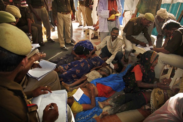 Pratapgarh: Police officers make records as the bodies of victims are seen after a stampede at Kripalu Maharaj's Ashram in Kunda near Pratapgarh, Uttar Pradesh on Thursday. Scores of people were killed and dozens of others injured in the stampede after thousands of people jostled each other to get free clothes and utensils being distributed at the Ashram. PTI Photo (PTI3_4_2010_000110B)